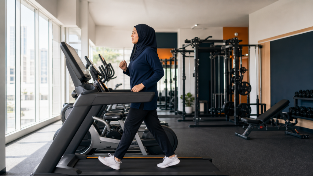 Seorang wanita berjalan laju di treadmill sebagai contoh cardio praktikal untuk fat loss.